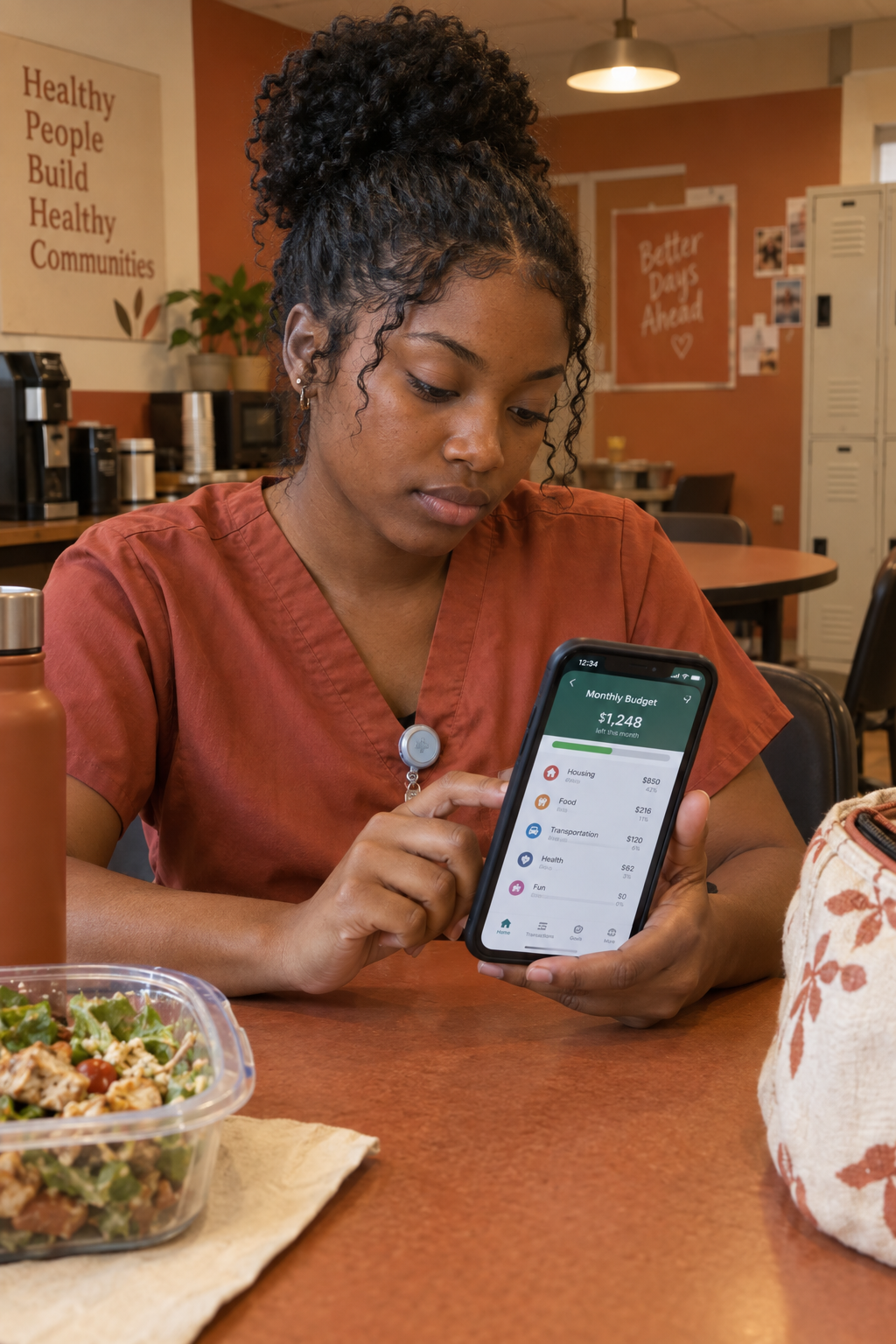 Young Black woman in nursing scrubs budgeting on her phone during a break